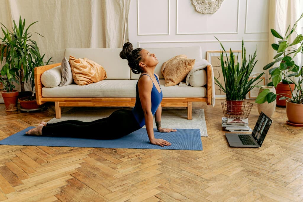 Yoga teacher practicing at home with laptop